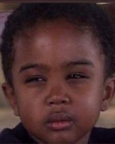 a close up of a young child wearing a black shirt and looking at the camera