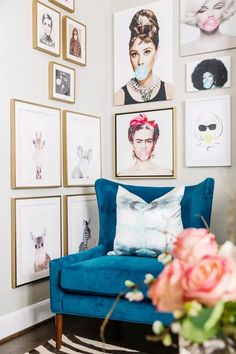 a living room with pictures on the wall and a blue chair in front of it