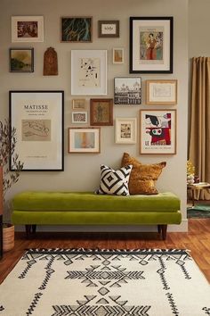 a living room filled with lots of framed pictures on the wall above a green couch