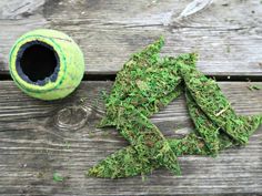 a ball and some grass sitting on top of a wooden table next to a planter