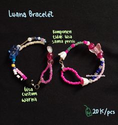 two bracelets with different colored beads and charms attached to each other on a black background