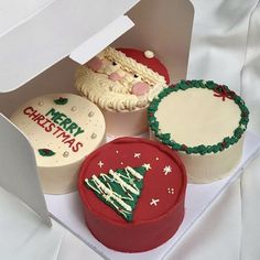 three decorated cupcakes in a white box