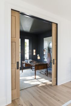 an open door leading to a living room with a desk and chair in the corner