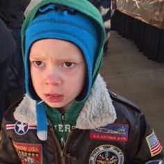 a young boy wearing an air force pilot's jacket and hat with patches on it