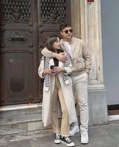 a man standing next to a woman in front of a door with her arms around him