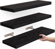 a hand is pointing at three black shelves