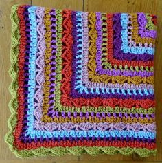 a multicolored crocheted dishcloth sitting on top of a wooden table