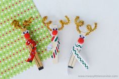 two wooden pegs with reindeer decorations on them sitting next to green polka dot paper