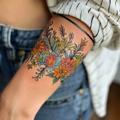 a woman's arm with flowers and leaves tattooed on the side of her arm