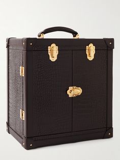 a black suitcase with gold handles and two doors on the front, sitting upright against a white background