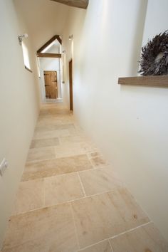 a narrow hallway with white walls and tan tile flooring