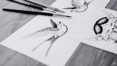 three birds are drawn on white paper next to some black and white ink pencils