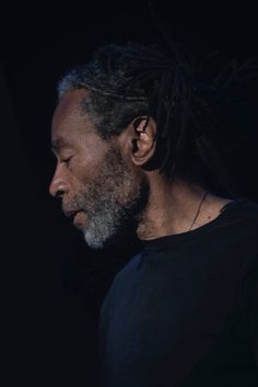 a man with dreadlocks standing in the dark