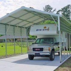 a truck is parked in front of a covered camper at a park with grass and trees