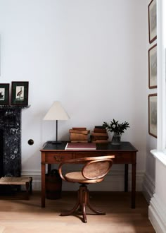 a room with a desk, chair and pictures on the wall above it is also a fireplace