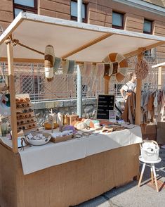 a table with food on it in front of a building and other items for sale