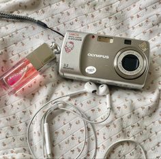 a camera and headphones are laying on a bed with the cord plugged in