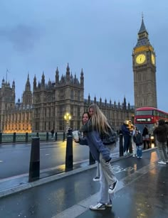 two people standing on the sidewalk in front of big ben