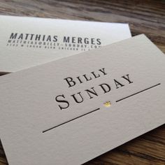 two business cards with the words billy sunday written on them, sitting on a wooden table