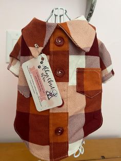 a brown and white checkered shirt hanging on a rack next to a light switch