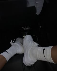 the person is wearing white socks and black nike shoes while sitting on a car seat