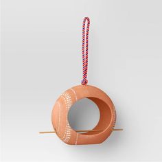 an orange object hanging from a string on a white wall with a red and blue cord