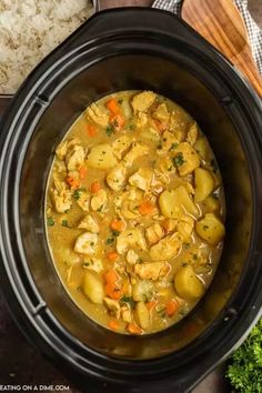 a crock pot filled with chicken and dumplings next to rice on a wooden cutting board