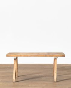 a wooden bench sitting on top of a hard wood floor next to a white wall