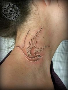 a woman's neck with a bird tattoo on it