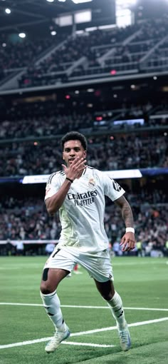 a soccer player is running on the field with his hand up to his face as he celebrates