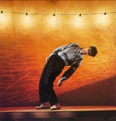 a man standing on top of a wooden floor in front of a wall with lights