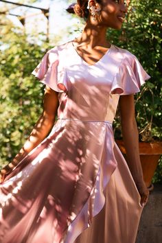 a woman in a pink dress is standing outside