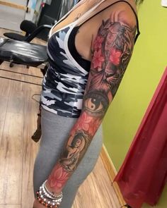 a woman with a tattoo on her arm and leg is standing in front of a mirror