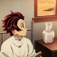 an anime character sitting at a desk with a book in front of him and a vase on the table