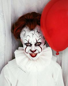 the clown is holding a red balloon in his hand