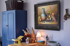 a painting hanging on the wall next to a blue cabinet