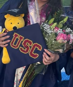 a girl in graduation gown holding flowers and a teddy bear with the word mssc on it