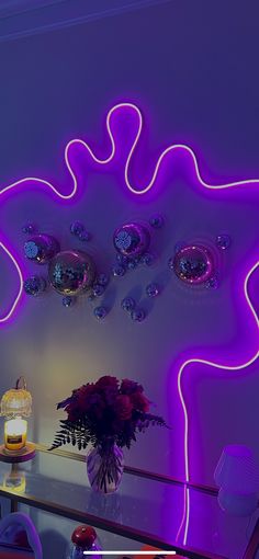 a room with purple neon lights on the wall and a vase filled with flowers in it