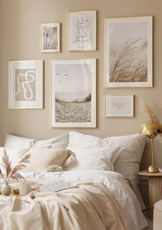 a bed with white linens and pictures on the wall