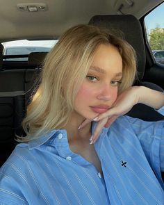 a woman sitting in the back seat of a car with her hand on her chin