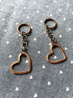 two metal heart shaped key chains on a fabric