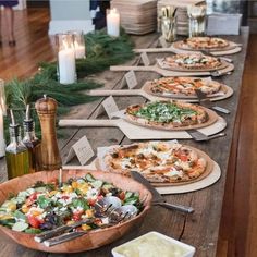 a long table topped with pizzas covered in cheese and toppings next to candles