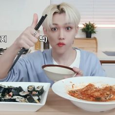 a person sitting at a table with bowls of food and chopsticks in front of them