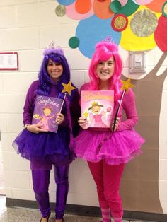 two girls dressed in costumes holding books and standing next to each other with balloons on the wall behind them