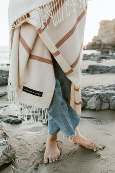 a woman standing on top of a beach covered in a blanket