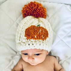 a baby wearing a crocheted hat with an orange pumpkin on it's forehead