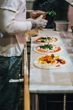 the man is making pizzas on the table