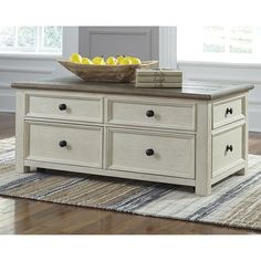 a bowl of lemons on top of a coffee table in a room with hardwood floors