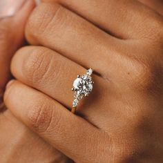 a woman's hand with a diamond ring on her finger and the other hand holding an engagement ring