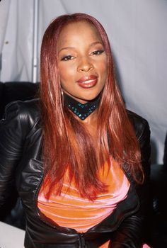 a woman with long red hair wearing a black leather jacket and choker around her neck